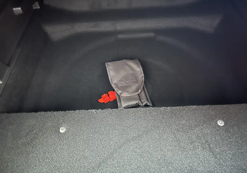 Détail du coffre noir du Peugeot 3008 Hybrid 2026 avec une sangle rouge et une pochette grise visible.