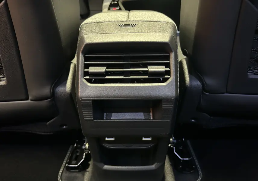 Vue rapprochée de la console arrière noire avec bouches d’aération et ports USB du Peugeot 3008 blanc Okenite.