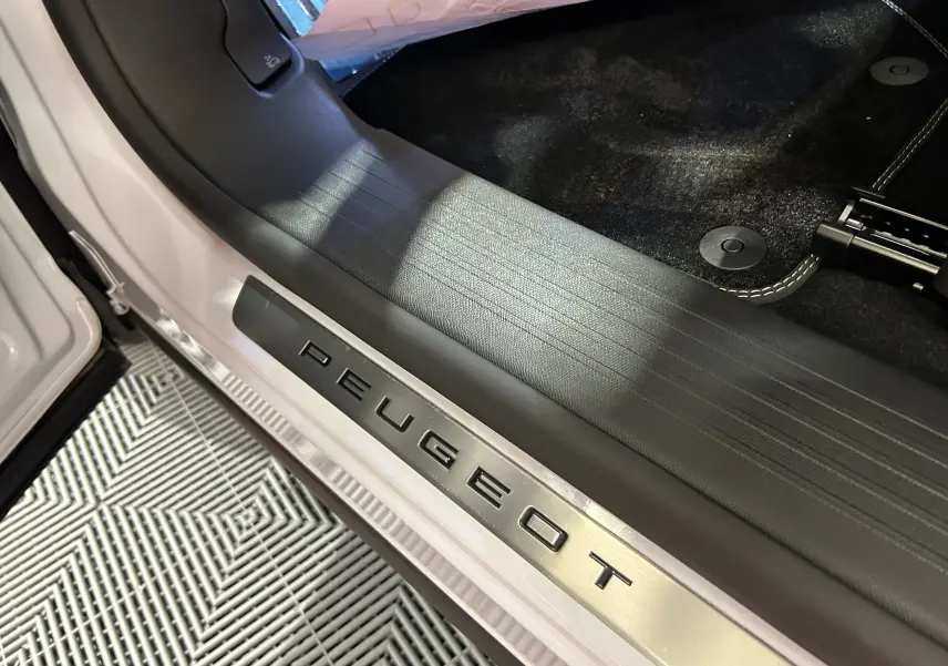 Gros plan sur la plaque de seuil de porte côté gauche en métal brossé avec logo Peugeot sur Peugeot 3008 blanc Okenite.