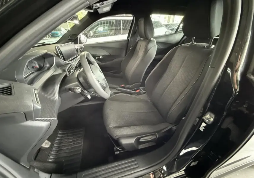 Vue intérieure côté conducteur du Peugeot 2008 noir perla 2025, montrant sièges et tableau de bord moderne.