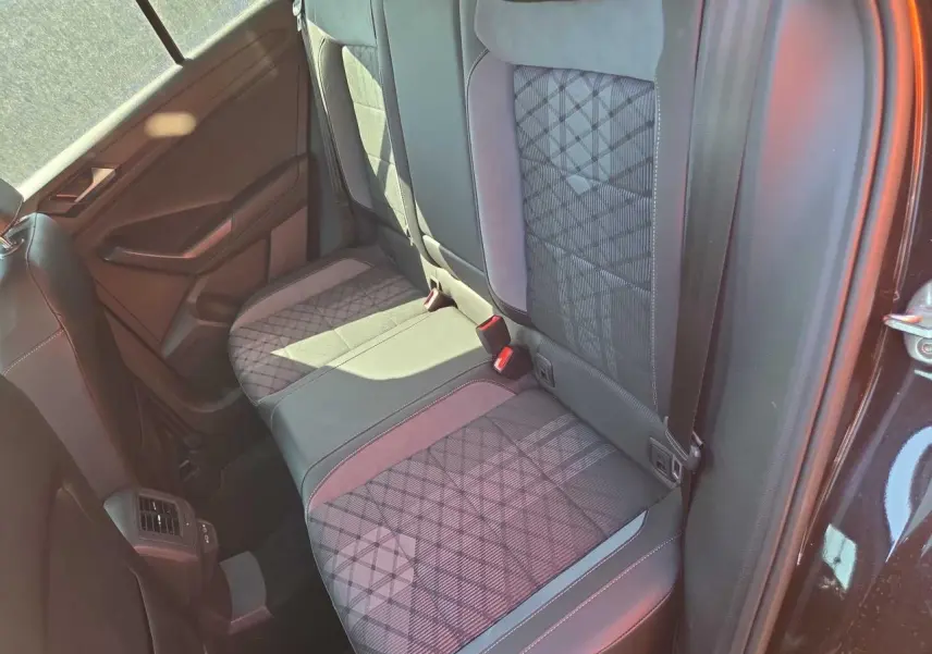 Vue intérieure côté droit de la banquette arrière du Volkswagen T-Roc noir métal avec sellerie tissu et surpiqûres grises.