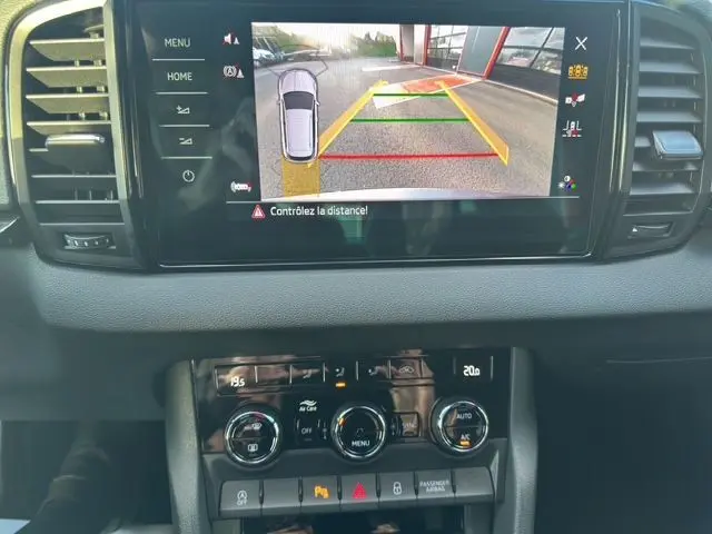 Écran central du Skoda Karoq 2025 montrant la caméra de recul avec guidage, tableau de bord et commandes climatisation visibles.