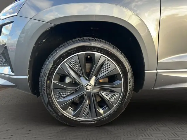 Gros plan sur la roue avant droite du Skoda Karoq gris graphite, mettant en valeur la jante alliage noire au design moderne.