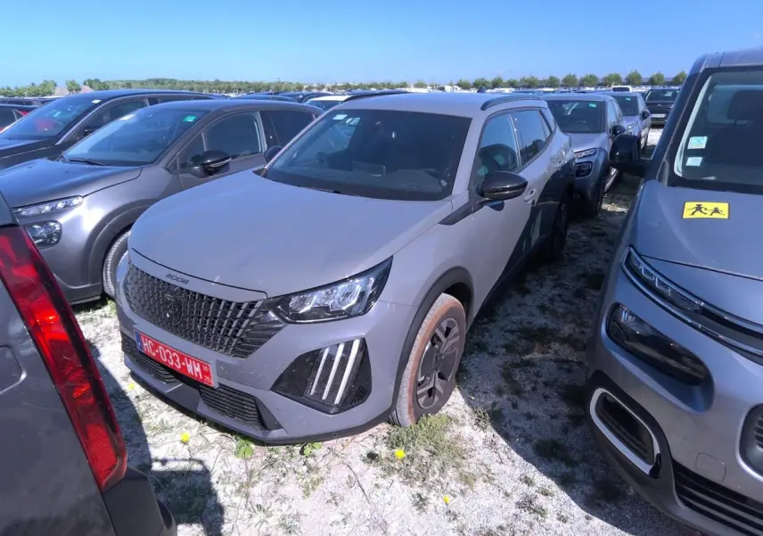 Peugeot 2008 gris clair vue 3/4 avant droit, avec calandre noire et feux LED à griffes distinctifs.