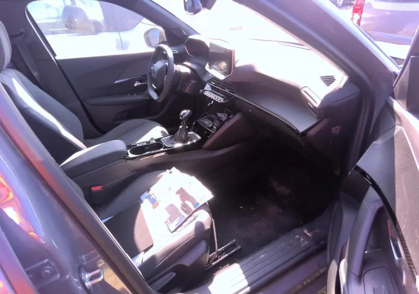 Intérieur avant droit du Peugeot 2008 gris clair 2025, avec tableau de bord carbone et boîte manuelle.