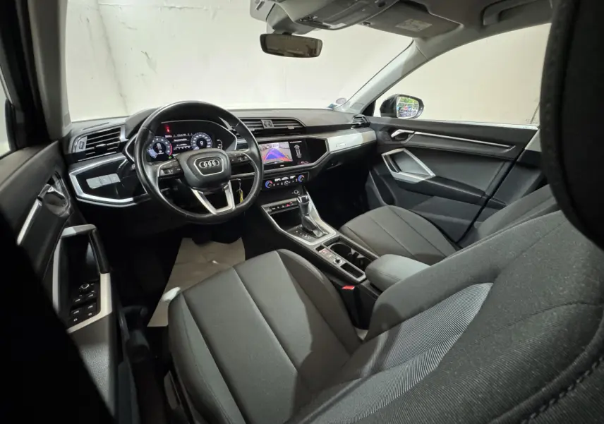 Intérieur noir de l'Audi Q3 35 TFSI 2022 vu côté conducteur, avec tableau de bord digital et écran central tactile.