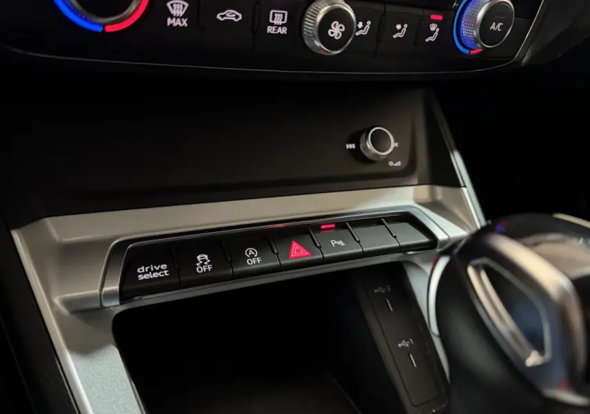 Gros plan sur la console centrale noire de l'Audi Q3 35 TFSI 2022 avec boutons de contrôle et levier de vitesses visible.