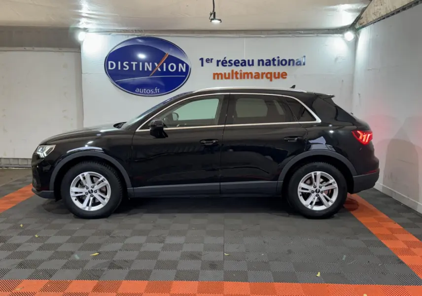 Audi Q3 noir vue de profil côté gauche dans un showroom avec éclairage et logo Distinxion en arrière-plan.