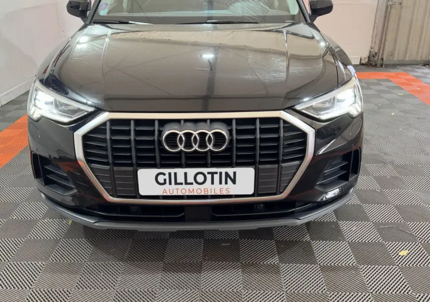 Vue frontale d'un Audi Q3 noir 2022 avec calandre hexagonale et phares LED allumés dans un garage.