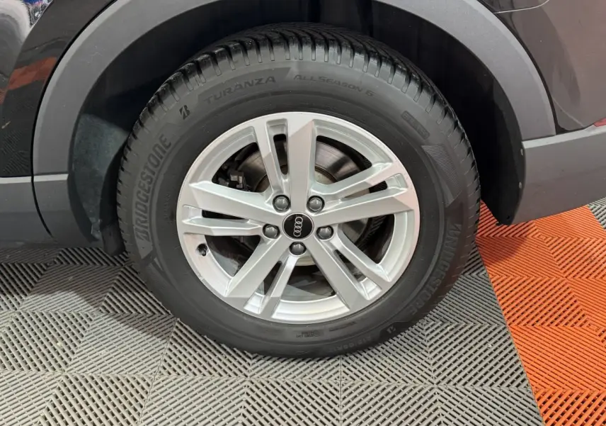 Gros plan sur la roue arrière droite avec jante argentée et pneu Bridgestone du SUV Audi Q3 noir.