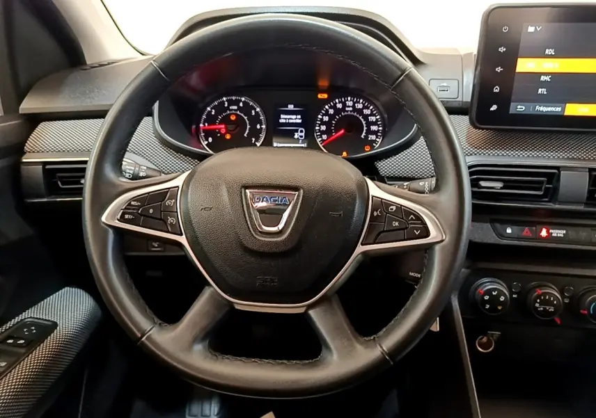 Vue rapprochée du volant noir de la Dacia Sandero 2022 avec tableau de bord et écran tactile visible à droite.