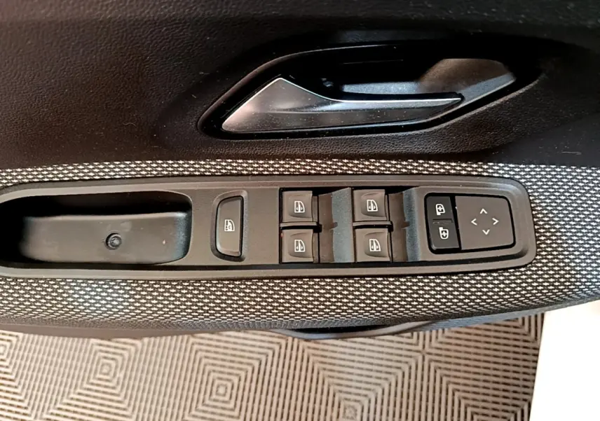 Gros plan sur la commande des vitres électriques et des rétroviseurs sur la porte côté conducteur d'une Dacia Sandero Confort TCe 90 2022.