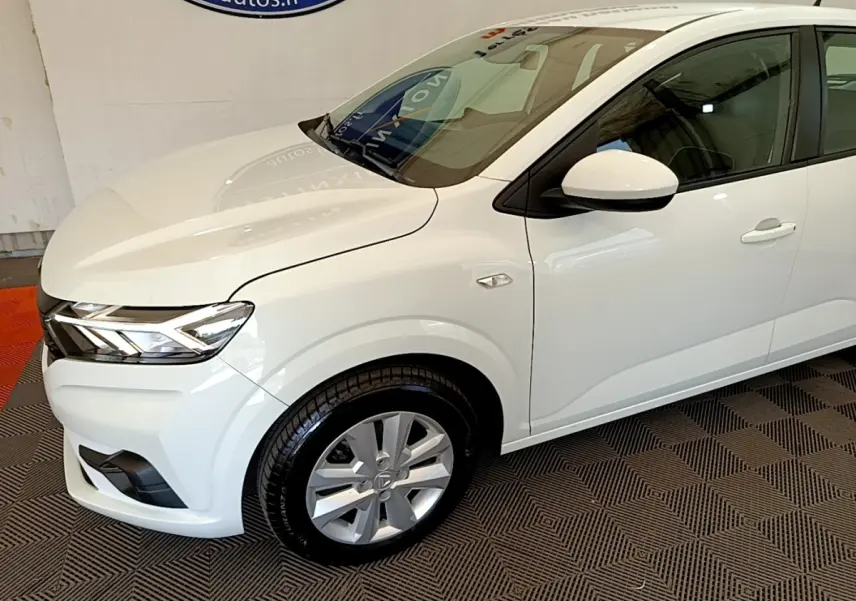 Vue 3/4 avant droit d'une Dacia Sandero blanche 2022 avec phares LED et jantes alliage visibles.