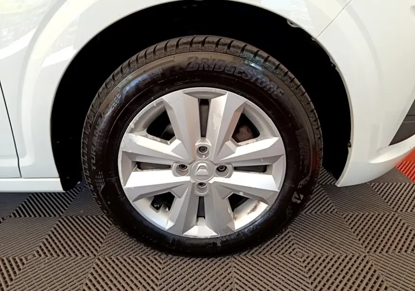 Gros plan sur la roue avant droite d’une Dacia Sandero blanche avec jante argentée et pneu Bridgestone.