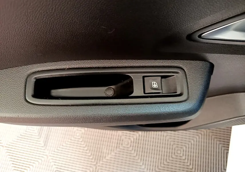 Poignée intérieure de porte côté conducteur de Dacia Sandero blanc, avec bouton de commande de vitre électrique.