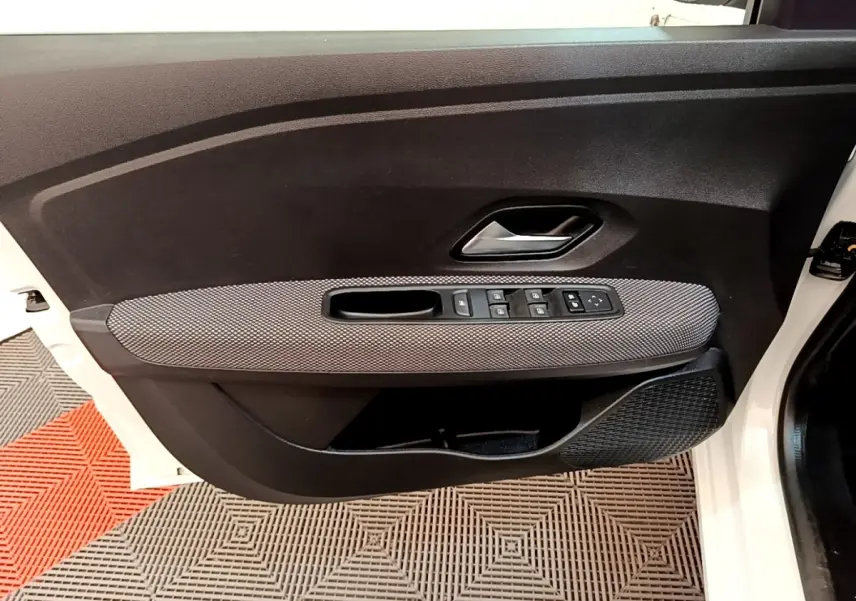 Vue intérieure de la porte avant gauche blanche de la Dacia Sandero 2022 avec commandes électriques et habillage gris.