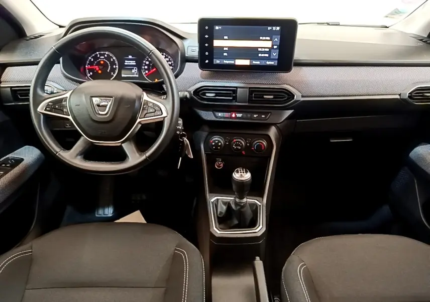 Vue intérieure frontale du tableau de bord et volant noir de la Dacia Sandero Confort TCe 90 avec écran tactile central.