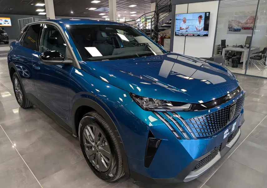 Peugeot 3008 Hybrid 145 ch en Bleu Obsession, vue 3/4 avant droit en intérieur avec calandre distinctive et phares LED.