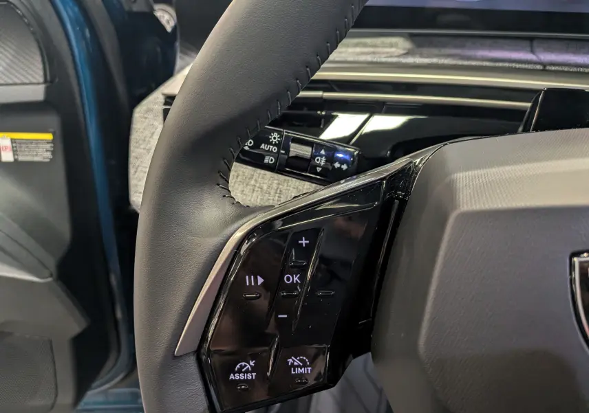 Gros plan sur la partie gauche du volant noir du Peugeot 3008 Hybrid 2026 Bleu Obsession, avec commandes intégrées.