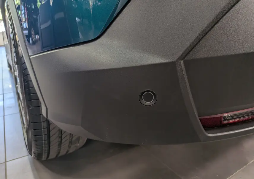 Gros plan sur le pare-chocs arrière droit bleu Obsession du Peugeot 3008 Hybrid avec capteur de recul visible.