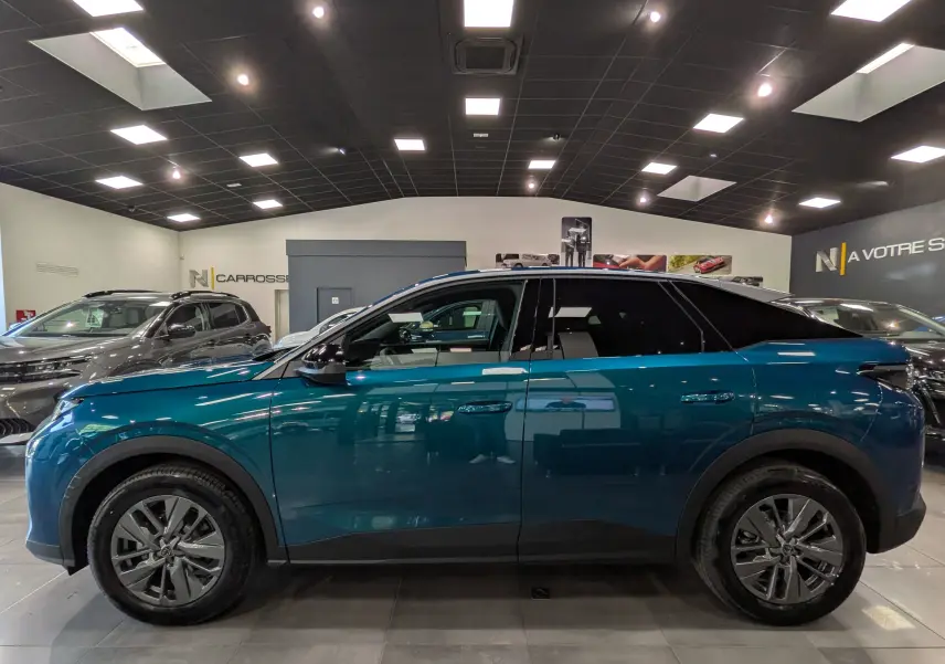 Vue de profil côté gauche d'un Peugeot 3008 Hybrid bleu Obsession en showroom, avec jantes alliage et vitres teintées.