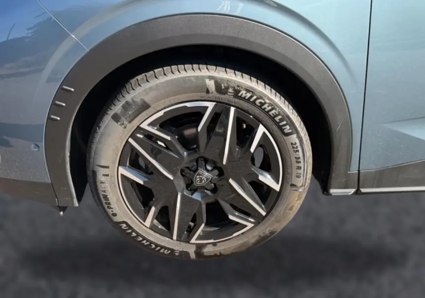 Gros plan sur la roue arrière droite du Peugeot 3008 bleu 2025 avec jante alu noire et détails Michelin visibles.
