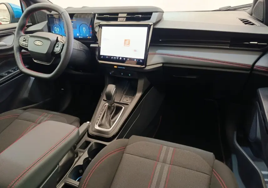 Intérieur avant du Ford Puma 2025 ST-LINE, tableau de bord noir avec coutures rouges et écran tactile central lumineux.