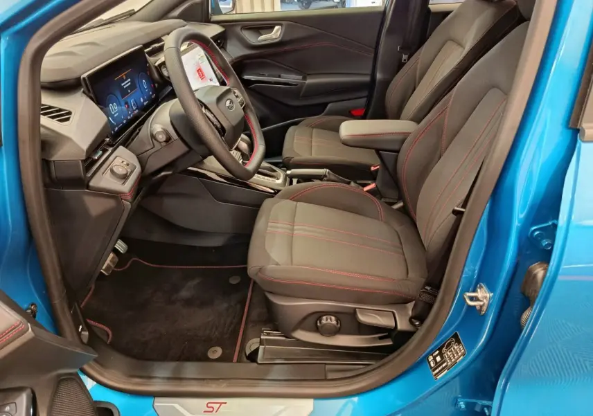Intérieur côté conducteur du Ford Puma bleu 2025, sièges noirs avec surpiqûres rouges et tableau de bord numérique.