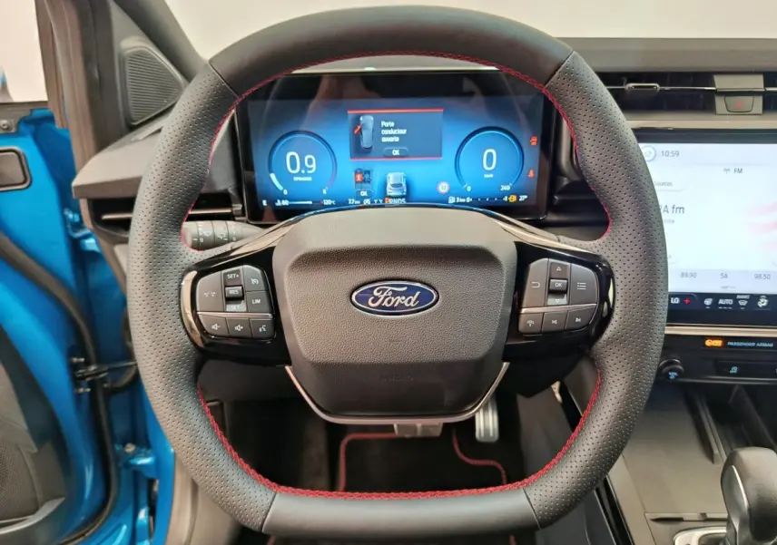 Vue frontale du volant en cuir noir avec surpiqûres rouges du Ford Puma bleu, tableau de bord numérique et écran tactile visibles.