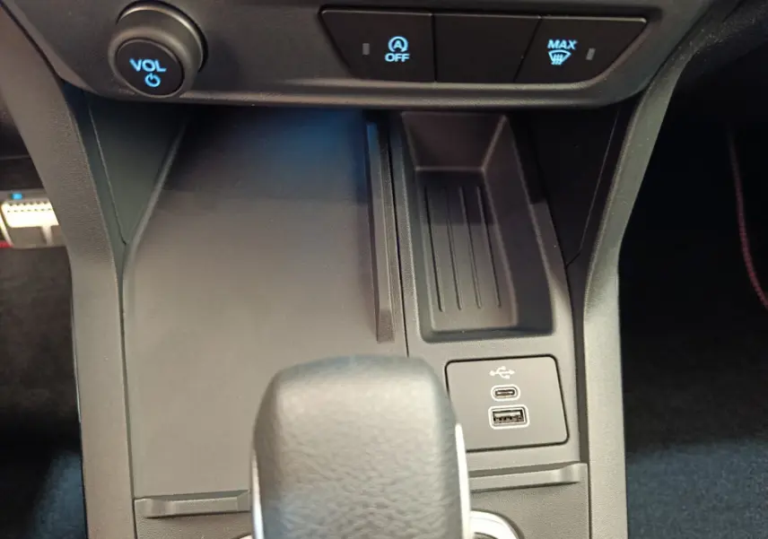 Gros plan sur la console centrale du Ford Puma 2025 montrant la boîte auto, ports USB et commandes de volume et désembuage.
