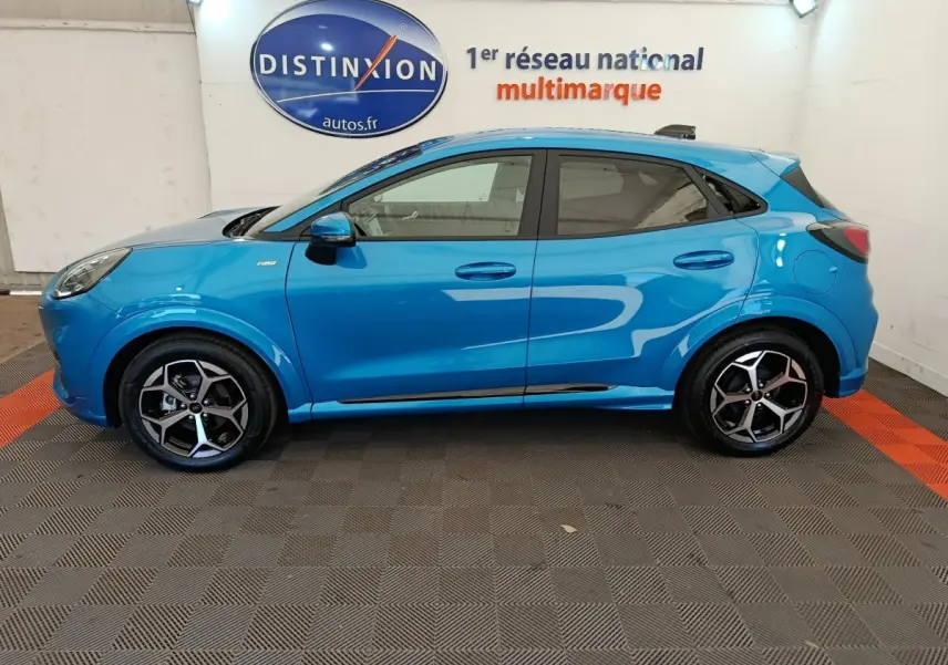 Profil côté gauche d'un Ford Puma bleu 2025 ST-LINE avec jantes alliage et logo Distinxion en arrière-plan.