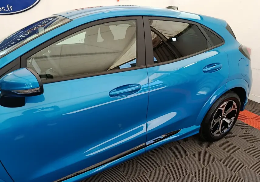 Vue latérale côté gauche du Ford Puma bleu 2025 avec jantes alliage et rétroviseurs noirs intégrant clignotants.