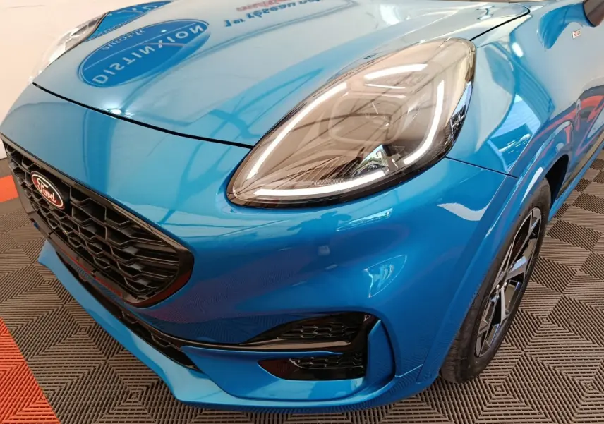 Vue 3/4 avant droit d'une Ford Puma bleu vif mettant en valeur son phare LED et sa calandre noire sportive.