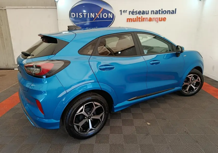Vue 3/4 arrière droite d'un Ford Puma bleu 2025 finition ST-LINE avec jantes alliage et vitres teintées.