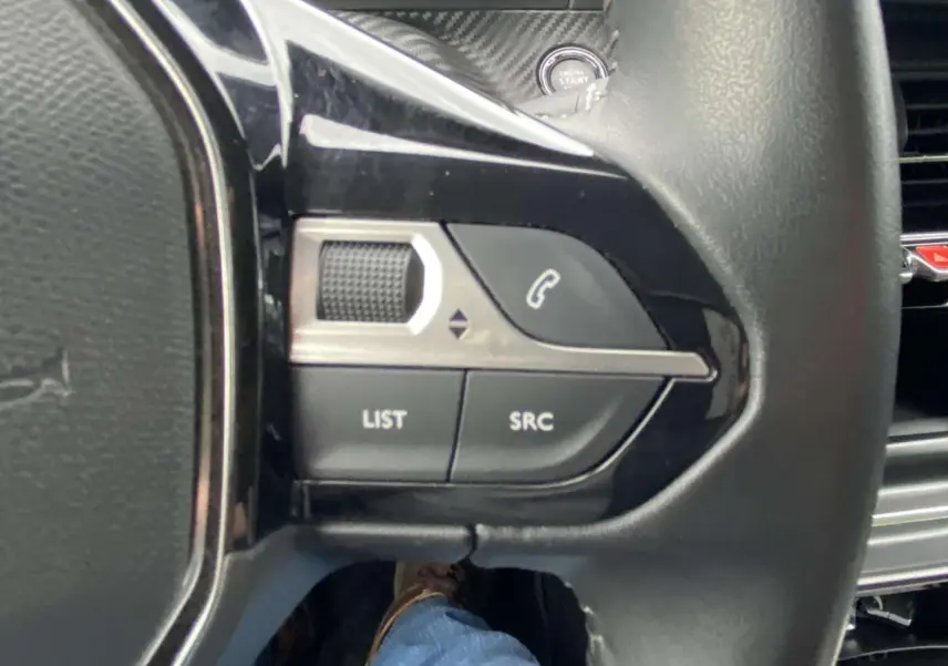 Gros plan sur les commandes gauche du volant noir de la Peugeot 208 2020, avec bouton appel et molette de réglage.