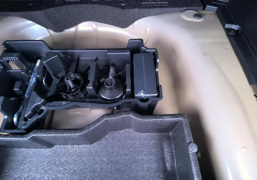 Vue rapprochée du coffre d’un Peugeot 2008 gris clair montrant le rangement pour outils et accessoires.
