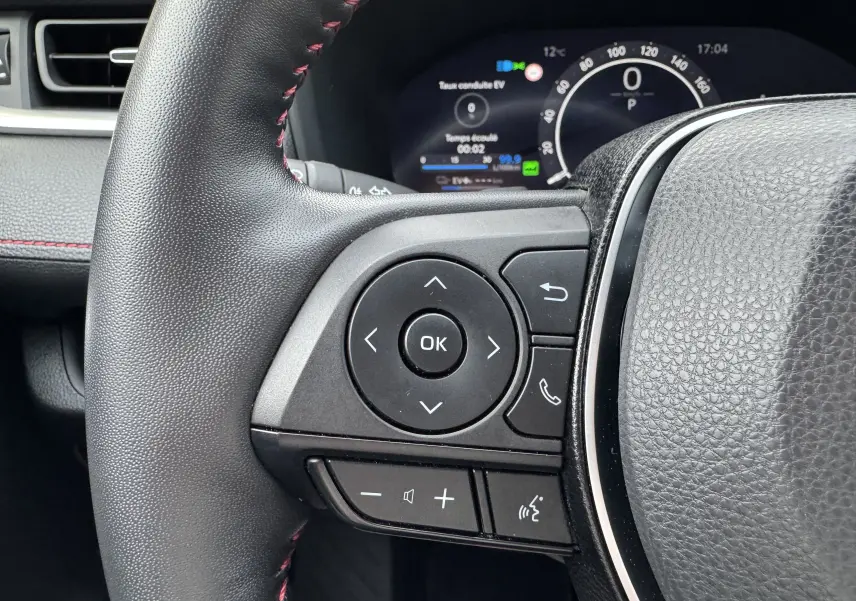 Gros plan sur les commandes gauche du volant cuir noir avec surpiqûres rouges du Suzuki Across hybride rechargeable 2023.