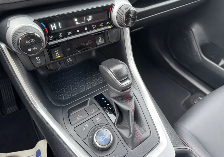 Gros plan sur la console centrale du Suzuki Across blanc 2023, avec levier de vitesse automatique et commandes climatisation.