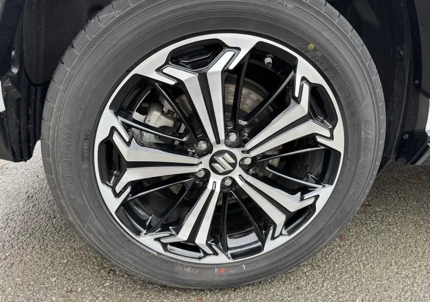 Gros plan sur la jante noire et argentée du Suzuki Across blanc 2023, mettant en valeur le logo central et le pneu Yokohama.