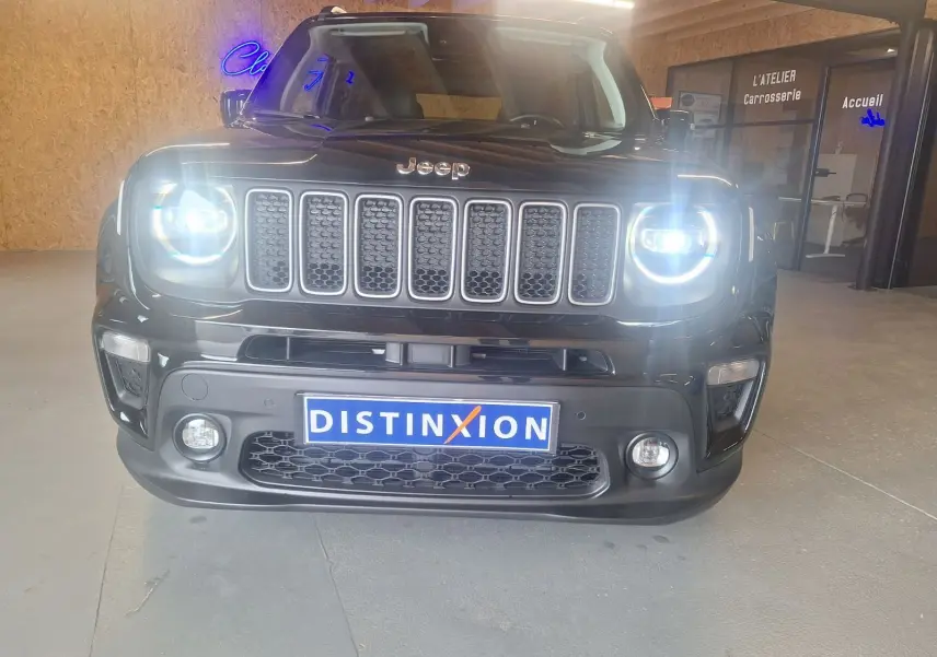 Vue de face d'un Jeep Renegade noir 2024 avec phares allumés et calandre à sept barres dans un showroom.