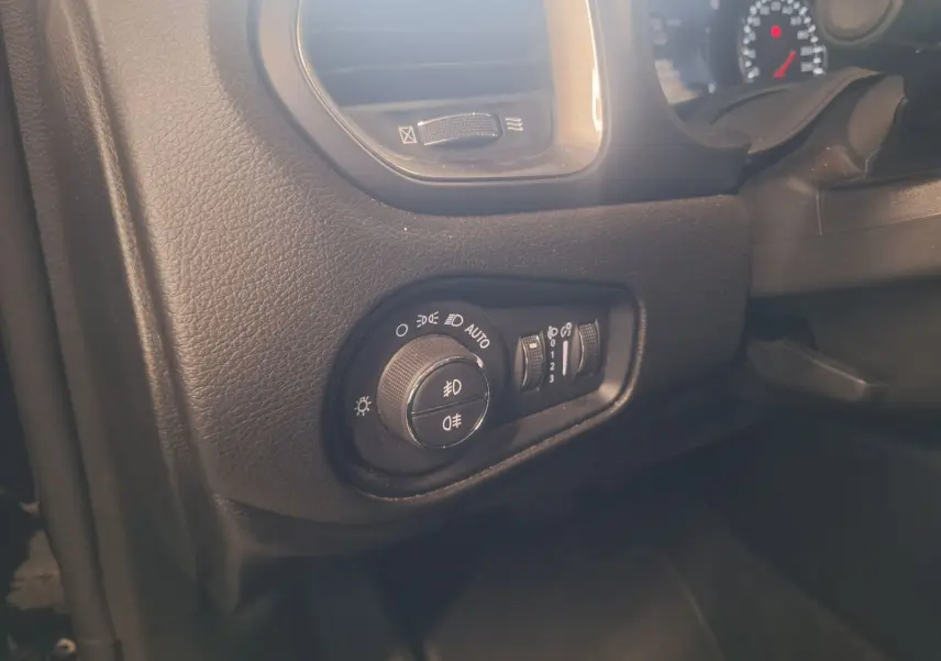 Gros plan sur les commandes d'éclairage à gauche du tableau de bord du Jeep Renegade noir 2024.