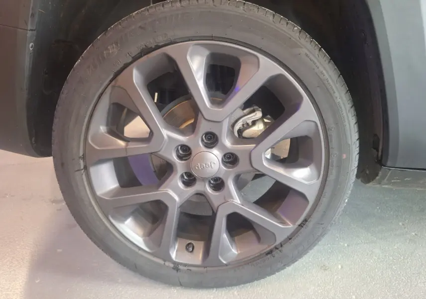 Gros plan sur la roue avant droite du Jeep Renegade noir 2024, mettant en valeur la jante alliage et le logo central Jeep.