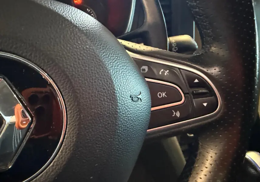 Gros plan sur le volant en cuir perforé noir de la Renault Mégane Break GT 2017, avec commandes intégrées côté droit.