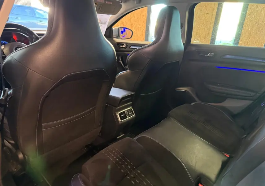 Vue intérieure arrière de la Renault Mégane Break GT 2017, sièges noirs en cuir et alcantara avec éclairage d'ambiance bleu sur la porte.