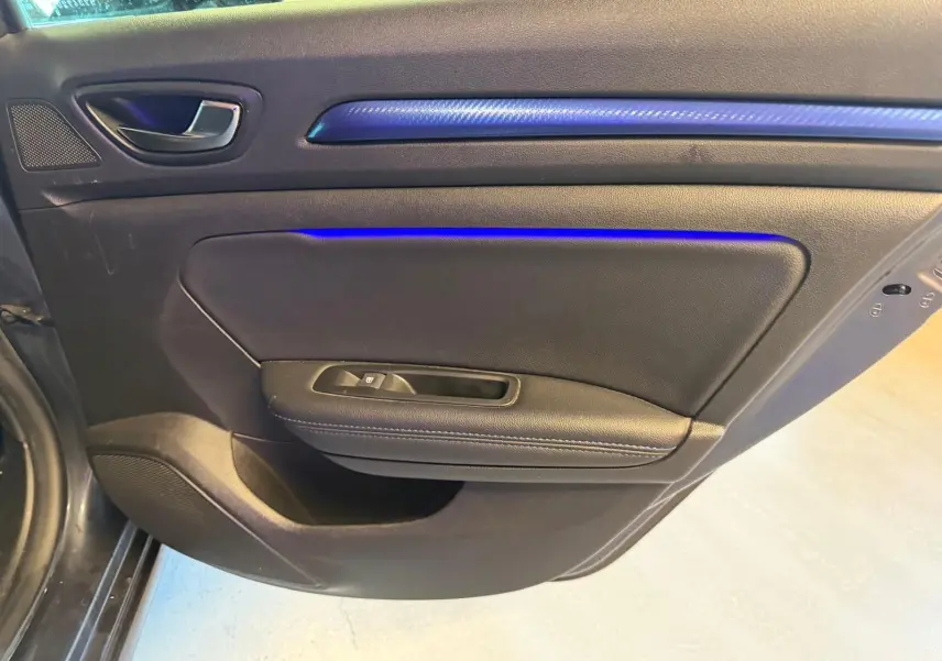 Vue intérieure côté gauche de la porte arrière d’une Renault Mégane Break gris avec éclairage d’ambiance bleu.
