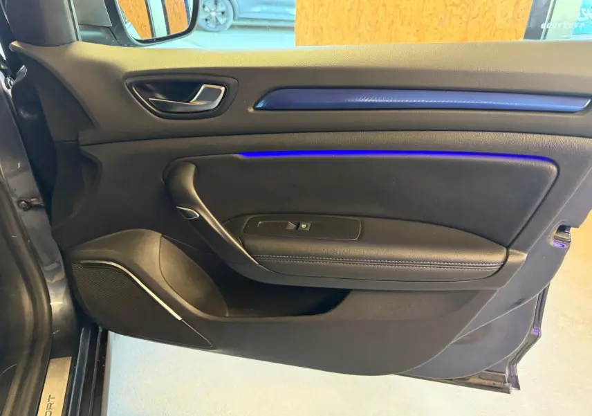 Vue intérieure de la porte avant gauche de la Renault Mégane Break GT gris, avec éclairage d'ambiance bleu subtil.