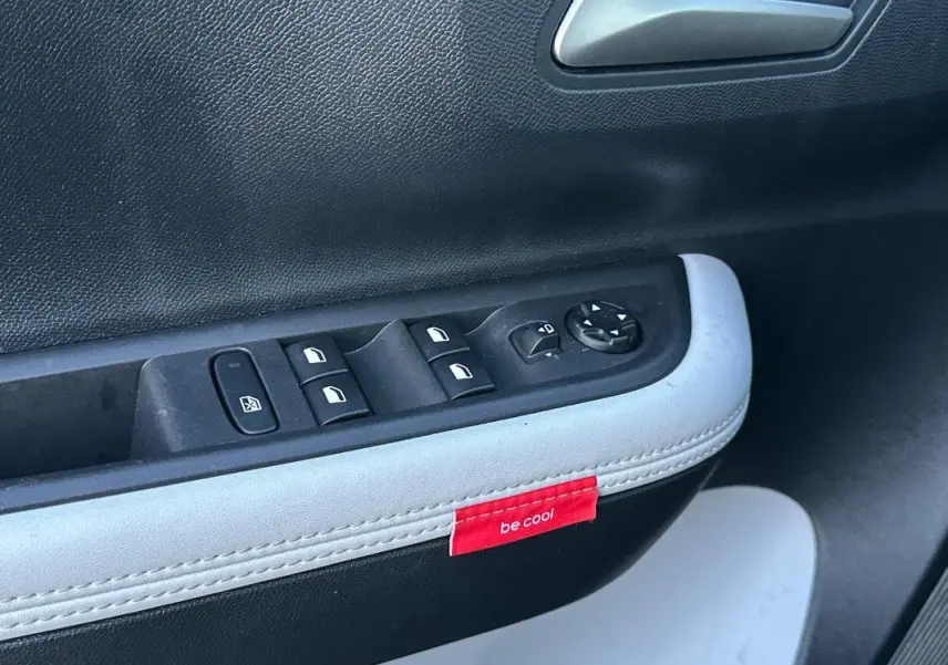 Détail de la porte côté conducteur de la Citroën C3 noire 2025, avec commandes électriques et étiquette rouge "be cool".