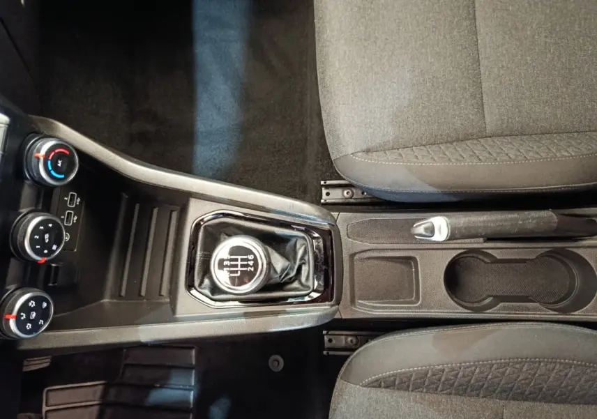Vue de dessus de la console centrale de la Renault Clio Business Blue dCi 100 blanche, avec levier de vitesses manuel et frein à main entre sièges gris.