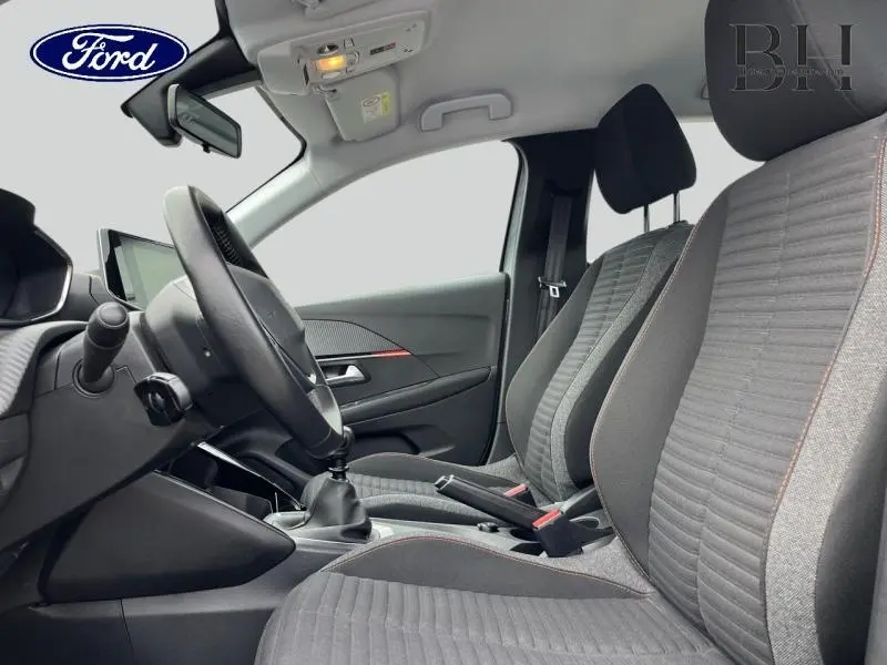 Vue intérieure côté conducteur de la Peugeot 208 1.5 BlueHDi 2020 avec sièges tissu gris et volant multifonctions.
