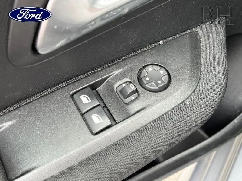 Gros plan sur les commandes de réglage des rétroviseurs et vitres côté conducteur d'une Peugeot 208 gris Artense.